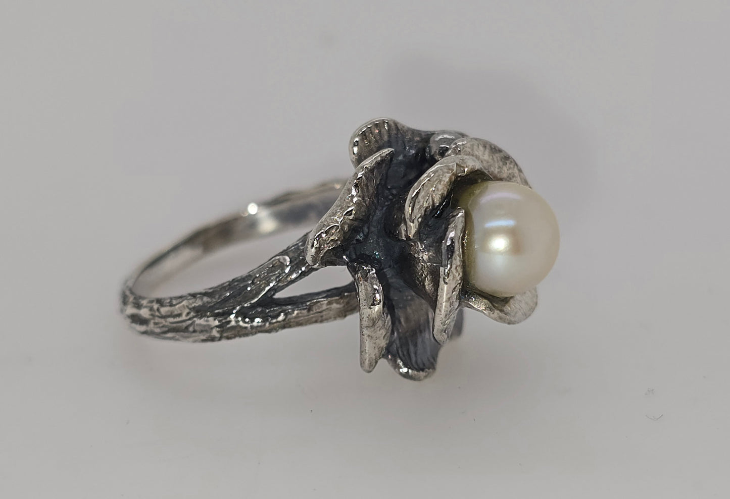 STERLING SILVER FLOWER RING WITH 7-7.5MM FRESHWATER PEARL CENTER.