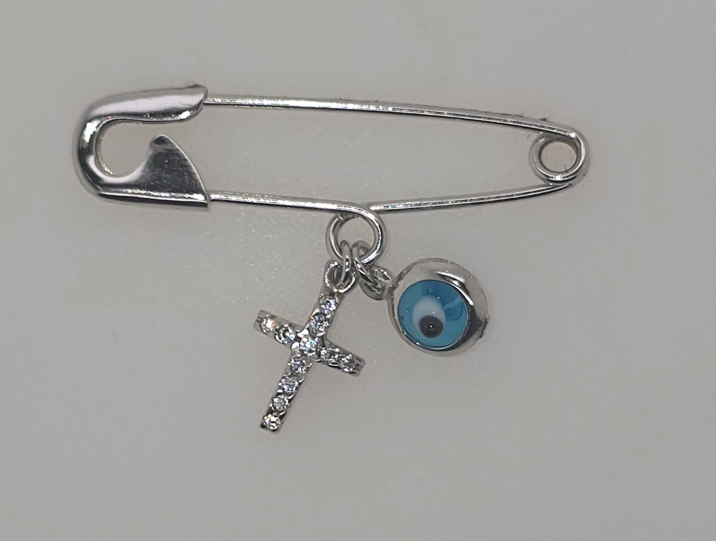9CT WHITE GOLD BABY PIN WITH EVIL EYE AND CUBIC ZIRCONIA CROSS.