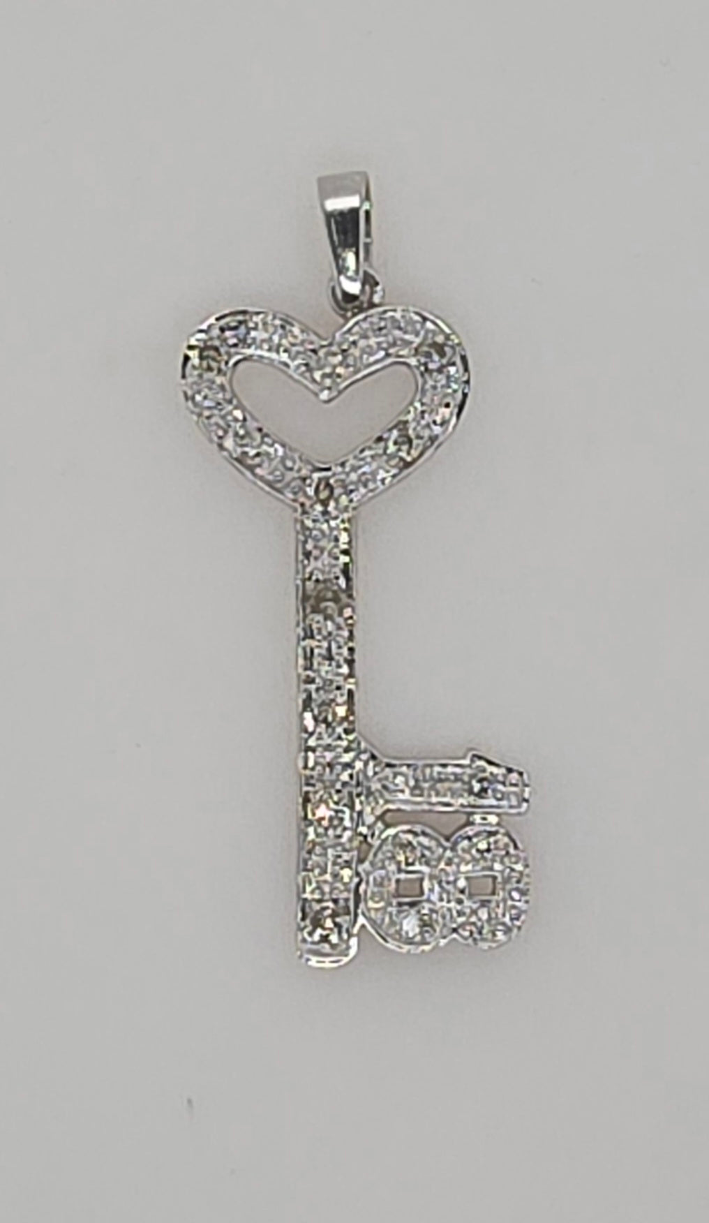 9CT WHITE GOLD DIAMOND 18 KEY PENDANT.