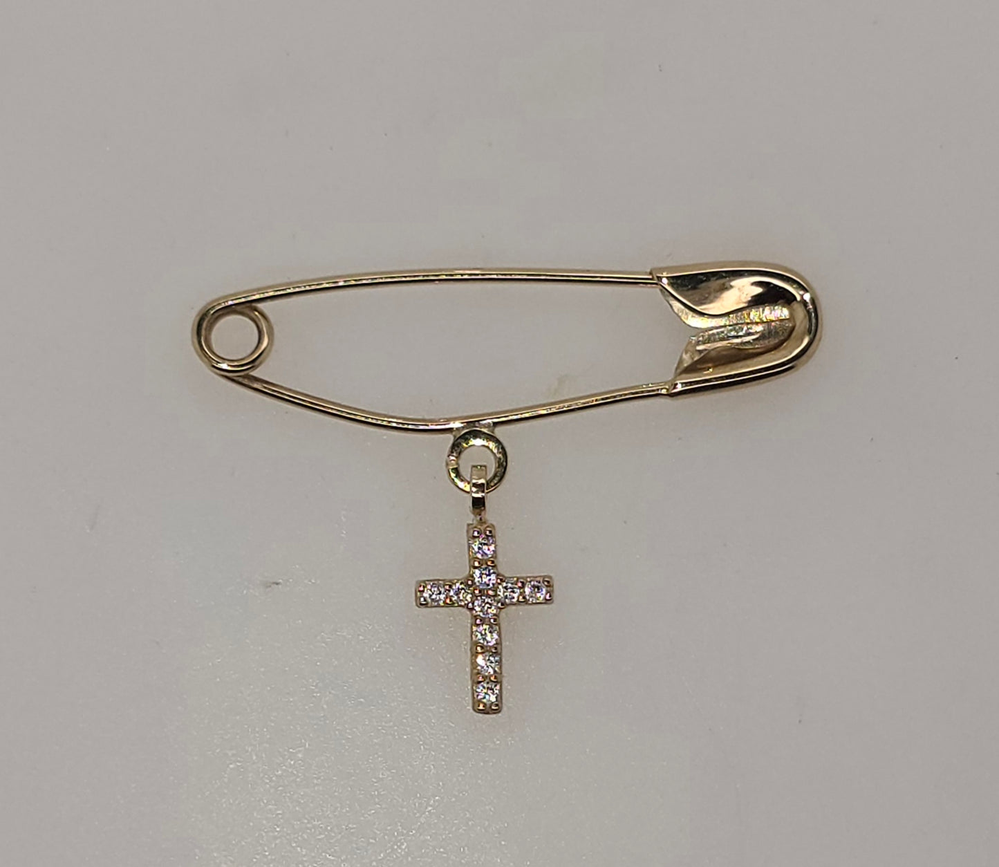 9CT YELLOW GOLD SAFETY PIN WITH CUBIC ZIRCONIA CROSS CHARM.