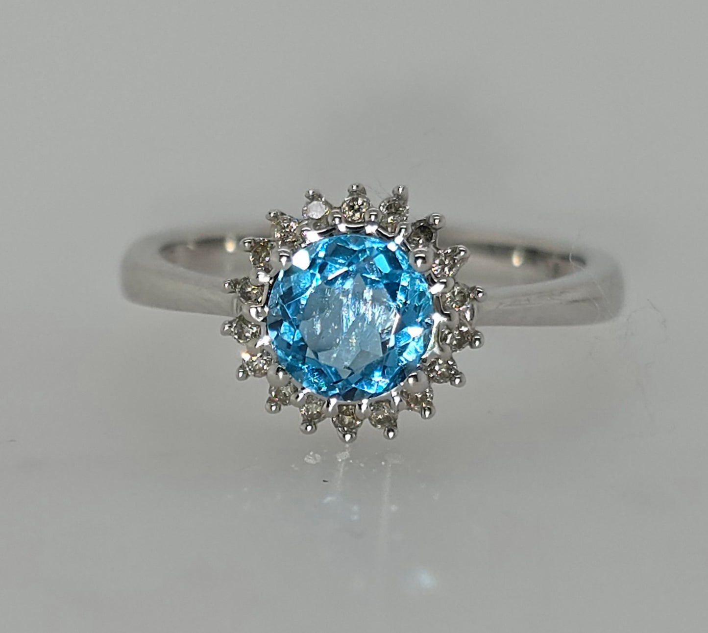 9CT WHITE GOLD BLUE TOPAZ AND DIAMOND HALO RING.