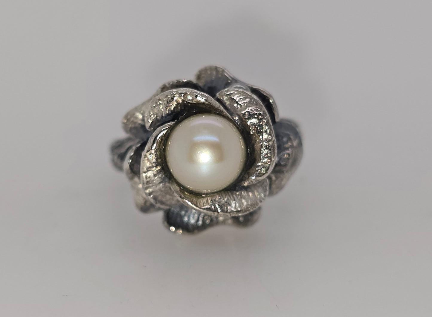 STERLING SILVER FLOWER RING WITH 7-7.5MM FRESHWATER PEARL CENTER.