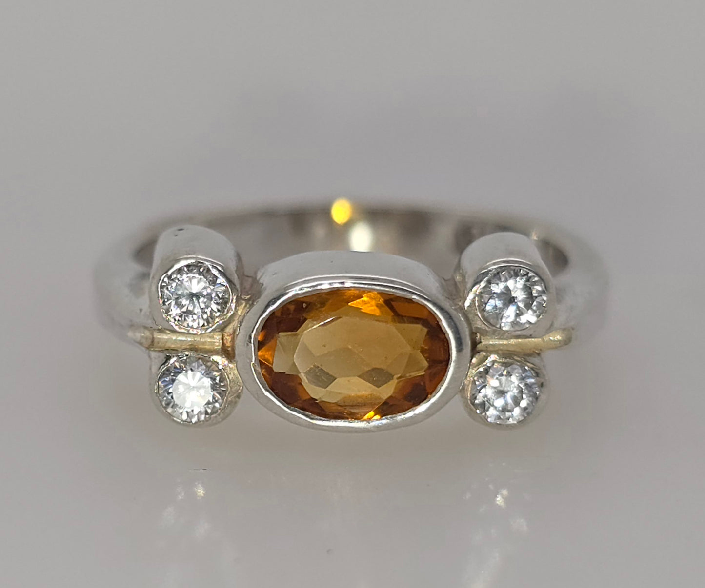 STERLING SILVER BEZEL SET CITRINE AND CUBIB ZIRCONIA RING.