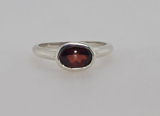 STERLING SILVER BEZEL SET 8 X 6 OVAL GARNET RING.