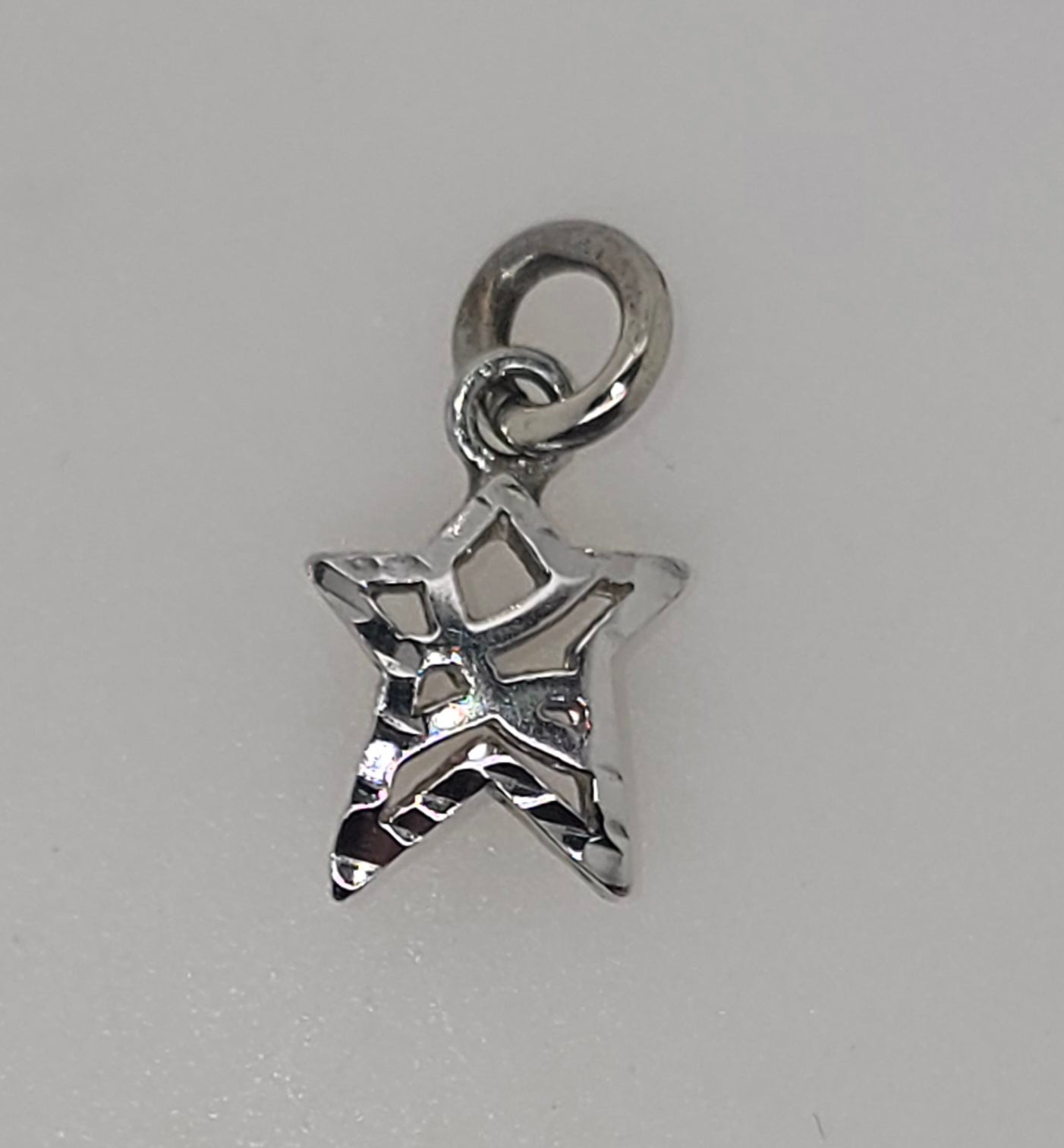 9CT WHITE GOLD 9MM STAR CHARM WITH CUT OUT DESIGN.