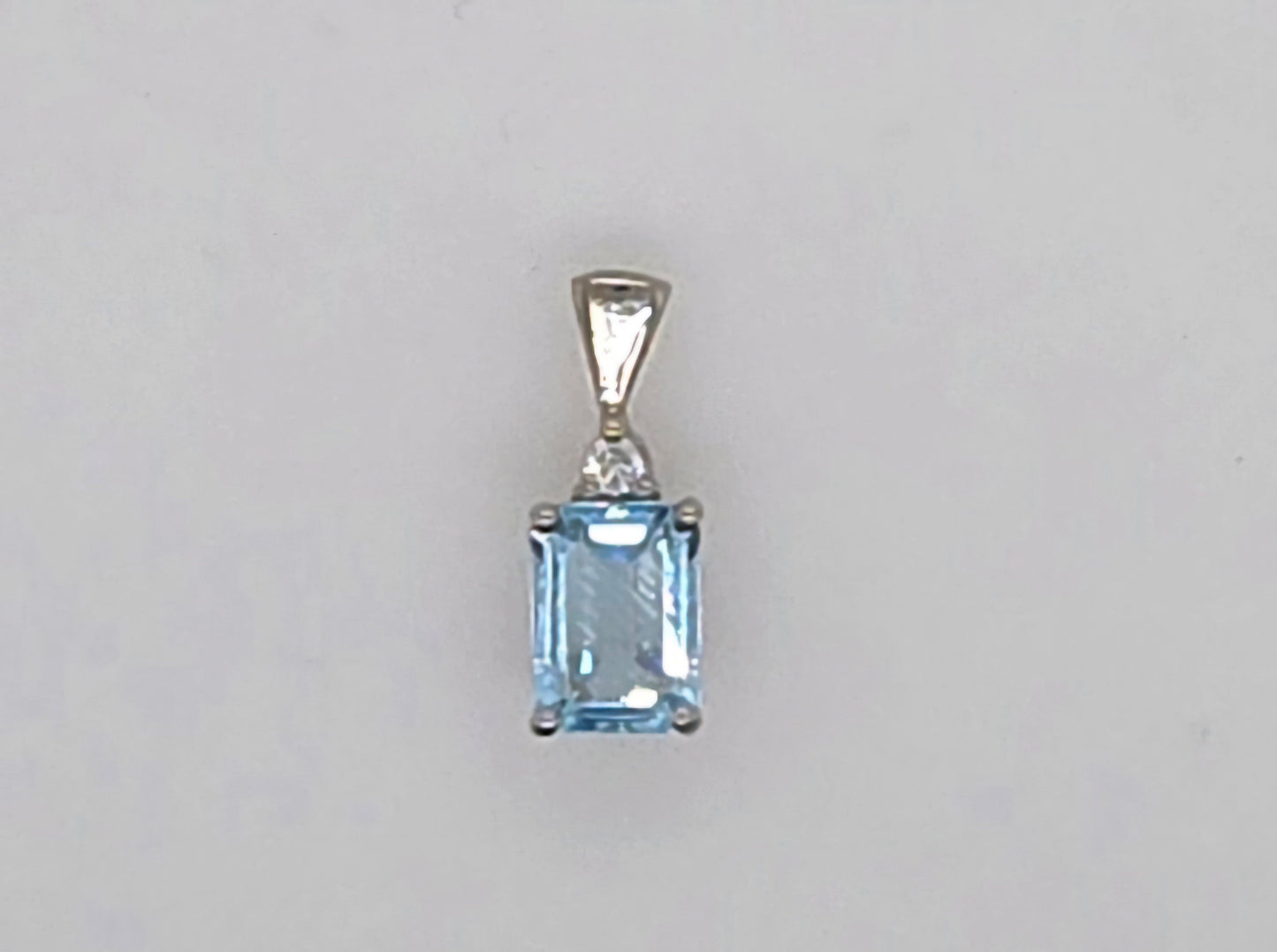 9CT WHITE GOLD 8 X 6MM EMERALD CUT BLUE TOPAZ AND DIAMOND PENDANT.