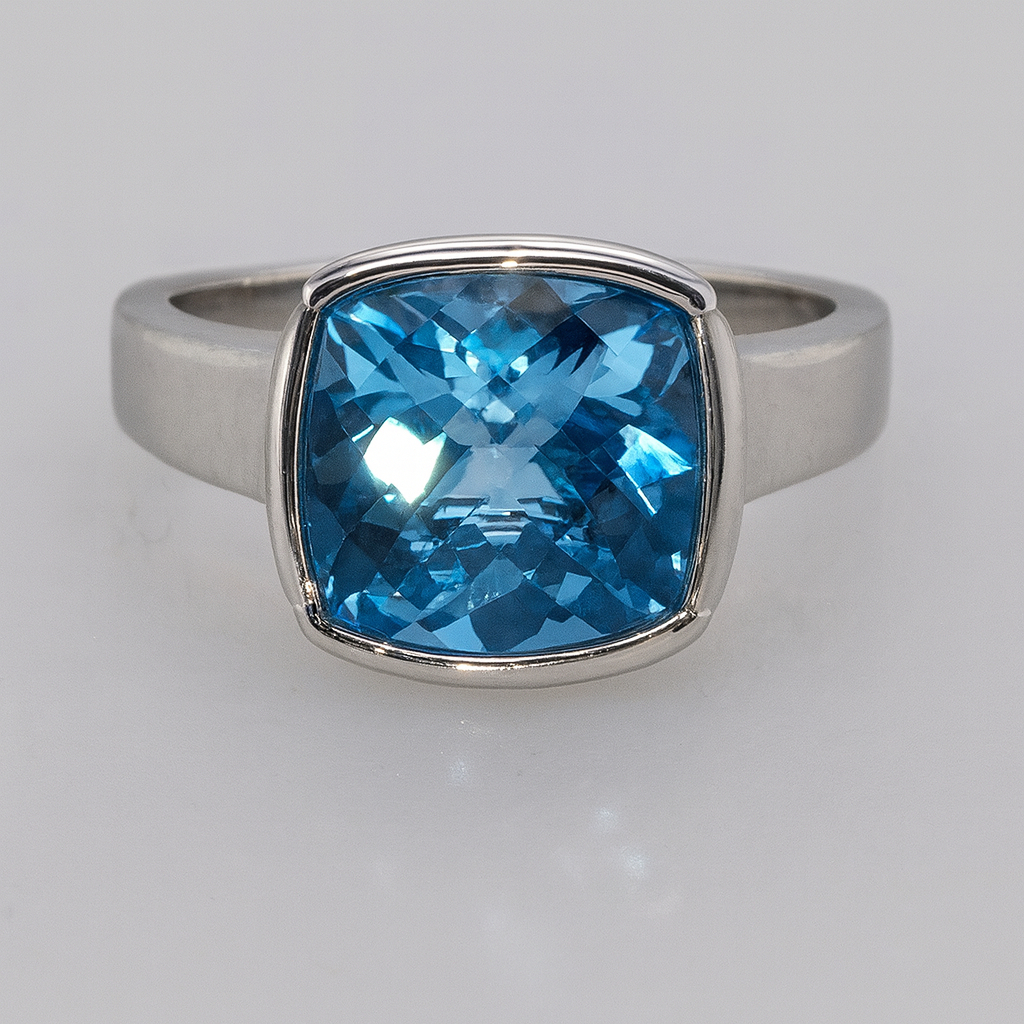 9CT WHITE GOLD BEZEL SET BLUE TOPAZ 9MM CUSHION CUT RING.